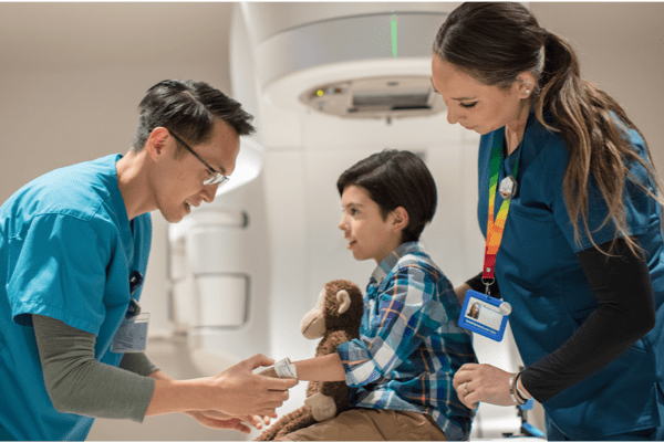 Boy with stuffed animal treated by doctor and nurse